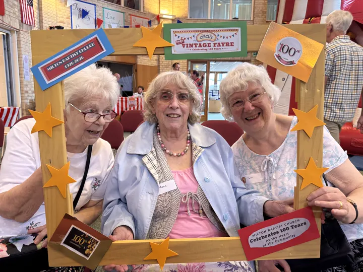 Three guests smiling through the decorated 100 Year Vintage Fayre photograph frame.