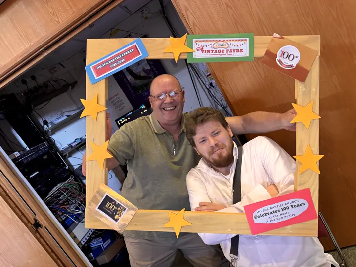 Two members of the technical team smiling through the Vintage Fayre photograph frame.