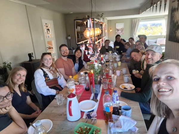 Friends gathered around a long dining table decorated with Norwegian flags.