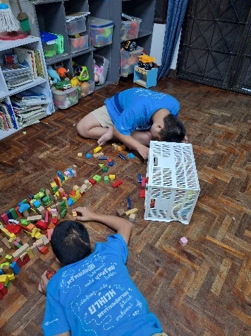 Two people playing with colourful building blocks at Hope Home.