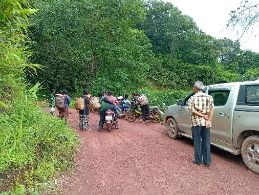People and vehicles on a rural road during a flood relief delivery.