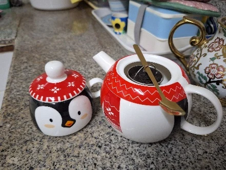 A cup of tea beside a penguin-shaped container.