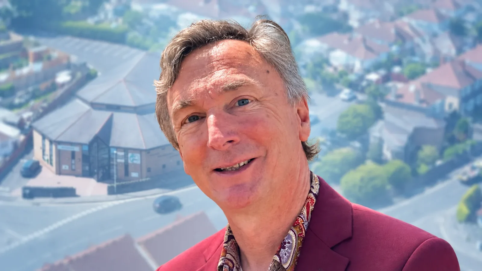 Gerry Stanton, with a softly faded aerial view of Milton Baptist Church behind him.