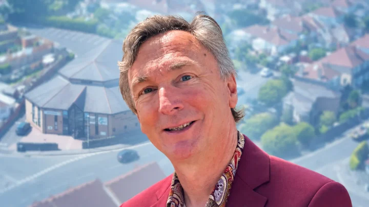 Gerry Stanton, with a softly faded aerial view of Milton Baptist Church behind him.